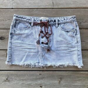 WE THE FREE Distressed Wash Denim Mini Skirt with Lace Up Detail and Raw Hem
